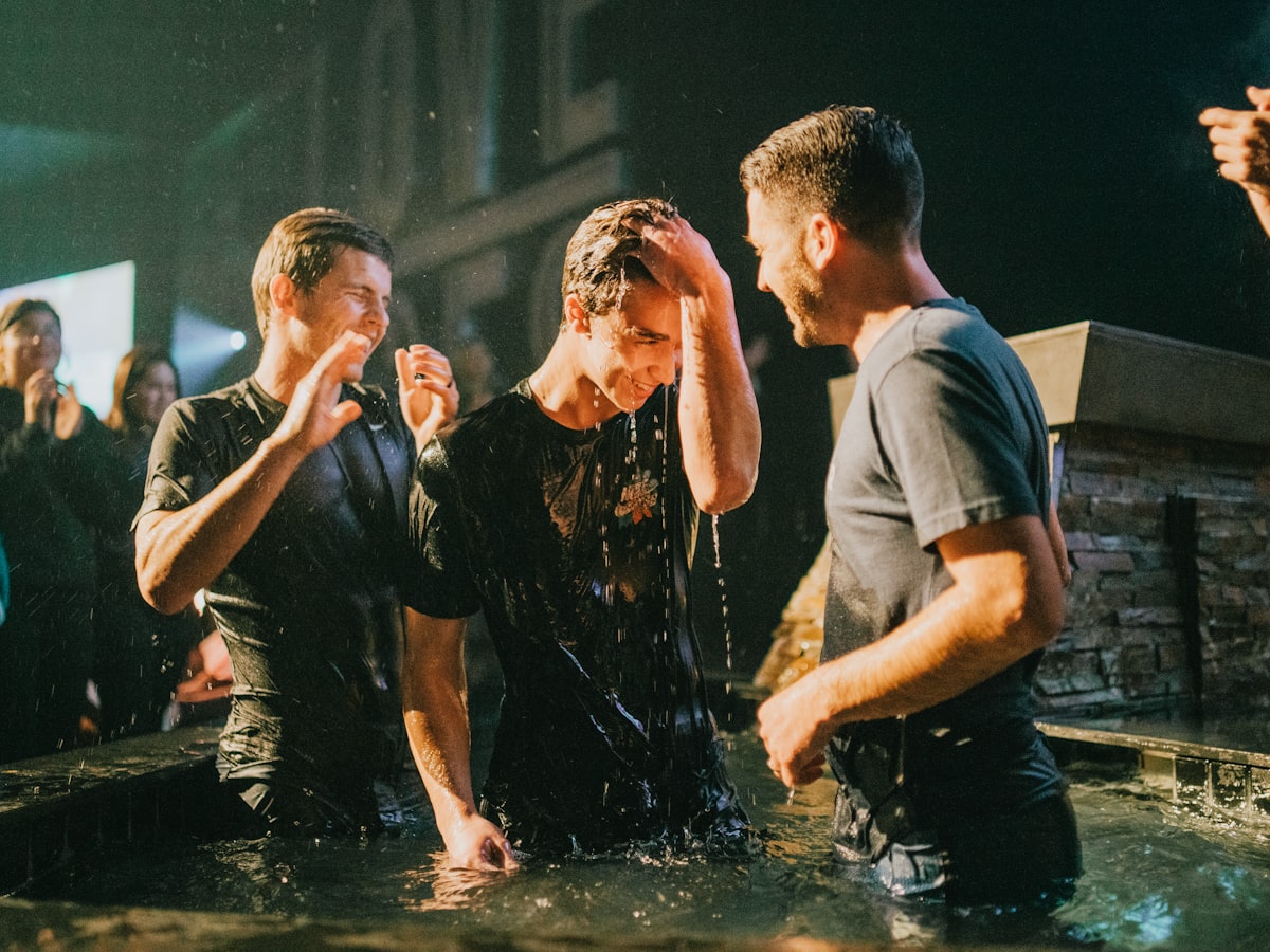 Joyful baptism moment with three men celebrating in the water